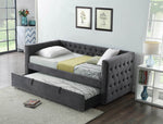 Gray upholstered trundle bed in a bedroom setting with decor elements.