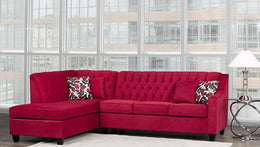 Red sectional sofa with patterned cushions in a room with large windows.