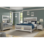 Silver bedroom set with bed, dresser, and nightstands in a room with gray walls and large windows.