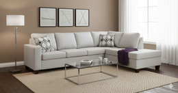 Gray sectional sofa in a living room with a coffee table, lamp, and decorative pillows.