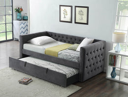 Gray upholstered trundle bed in a bedroom setting with decor elements.