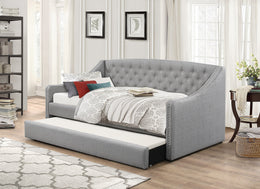 Gray tufted sofa bed with white bedding in a living room setting.