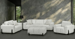 White sofa set with matching ottoman against a textured wall.